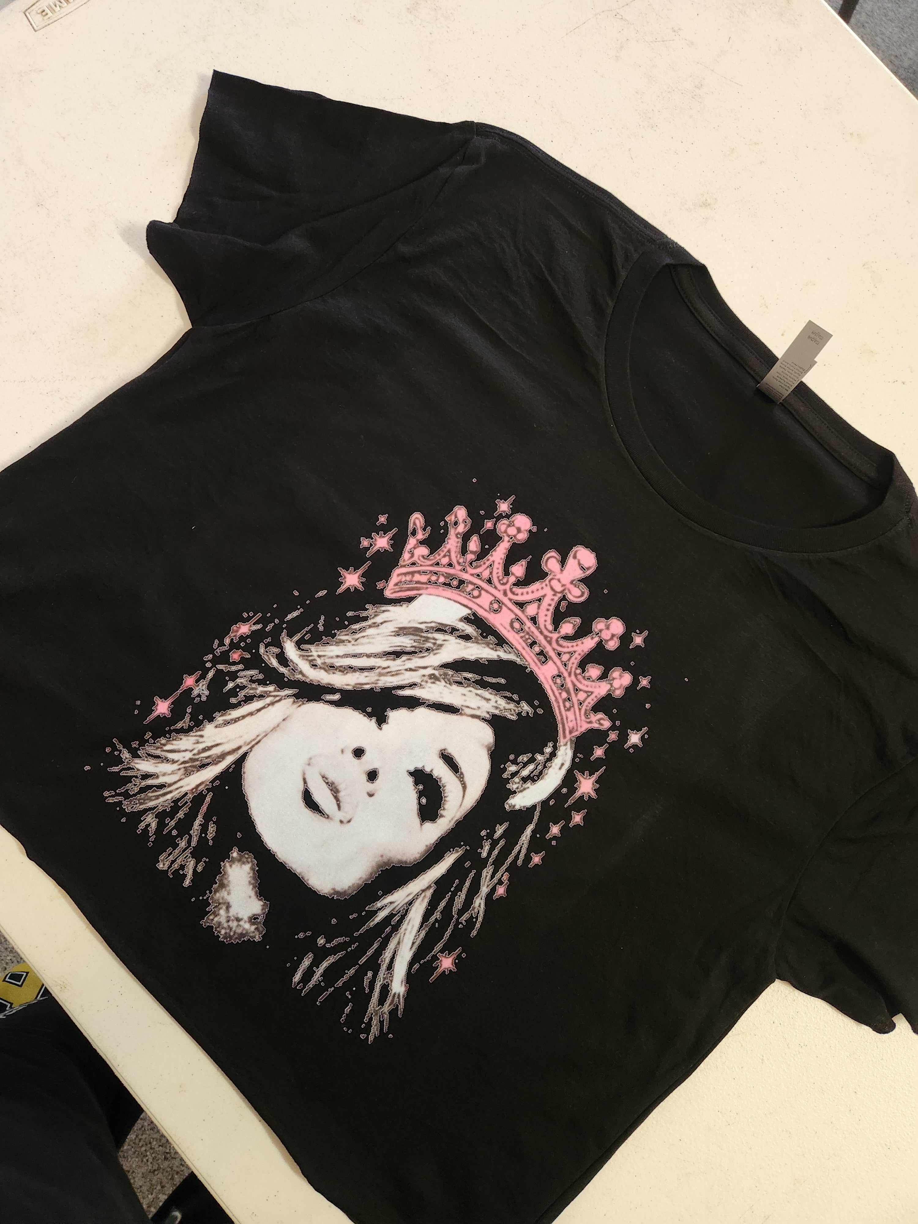Black t-shirt with a graphic of a woman's face wearing a pink crown